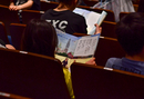 物語やテーマ曲の歌詞が掲載されたリーフレットを読みながら開演を心待ちにする様子が